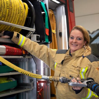 Brandweervrouw Marije poseert bij brandweerwagen