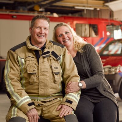 Brandweervrijwilliger en zijn vrouw zitten op een bankje in een kazerne