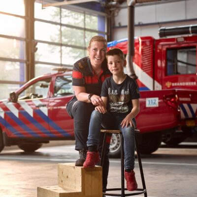 Casey en zijn moeder Thea, vrijwilliger Brandweer Haaglanden, poseren in brandweerkazerne