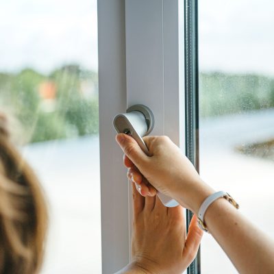 Hand die een raamklink opent om woning te ventileren