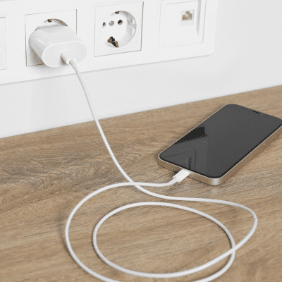 Telefoon op de grond aan de oplader die in het stopcontant zit