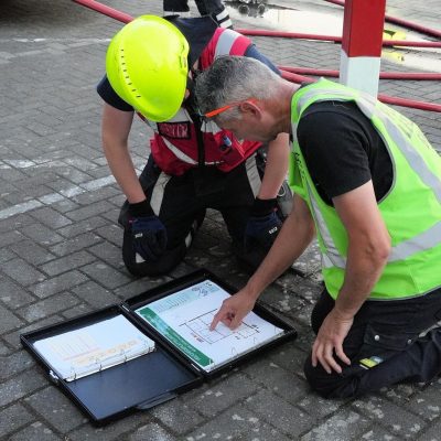 Twee mensen die naar een plattegrond aan het kijken zijn die op de grond ligt