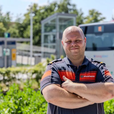 Brandweercollega geposeerd bij het station in Nijmegen waar een bus achterlangs rijdt