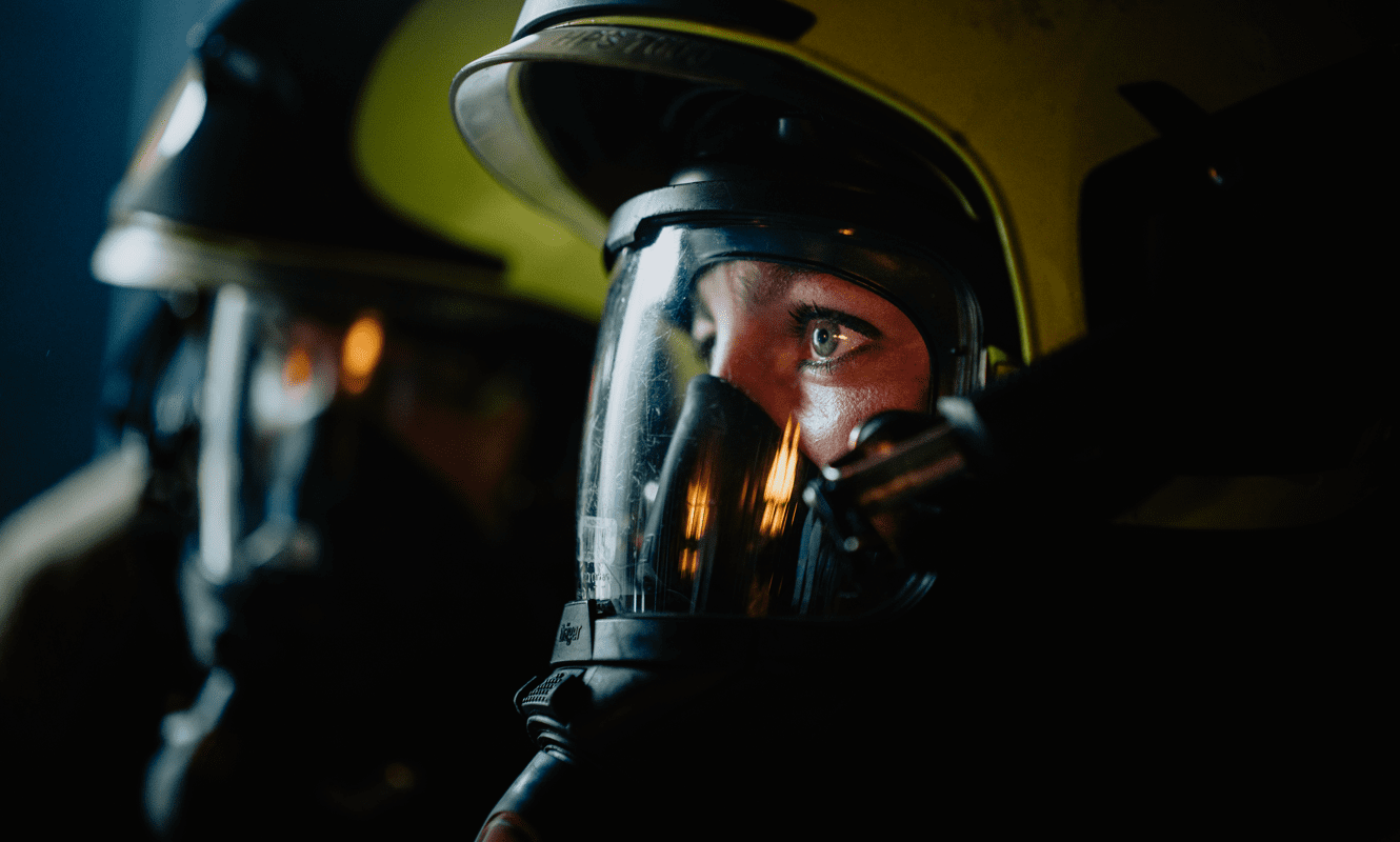 Close-up foto van het zijaanzicht van een brandweervrijwilliger met ademluchtmasker en brandweerhelm op