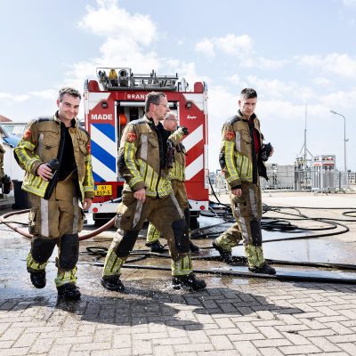 Brandweermannen lopen voor een brandweerauto