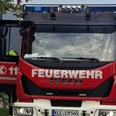 Een Duitse brandweerploeg staat opgesteld naast een brandweervoertuig tijdens de Internationale Brandweerwedstrijden in Wageningen. De deelnemers dragen ademluchtapparatuur en maken zich gereed voor een realistisch wedstrijdscenario.